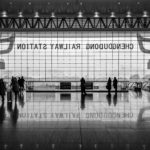 Black and white shot of station foyer with people and large window and reflection on floor