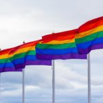 LGBTQ multi coloured flags under white sky