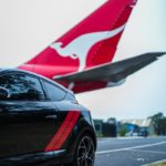 red and white airplane behind a black hatchback