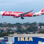 white and red Air Asia passenger plane above Ikea building during daytime