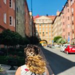 shallow focus photography of woman standing near buildings during daytime