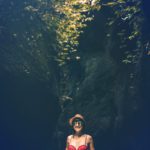 Young traveler woman in the jungle river. Rainforest of Bali island. Tourist adventure concept.