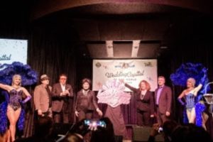 L: Composer Dan Slider, entertainer Dennis Bono, former Nevada Lieutenant GovernorLorraine Hunt-Bono, Clark County Clerk Lynn Marie Goya and producer Damian Costa flanked
by Las Vegas showgirls unveil 70th Anniversary of Wedding Capital of the World
signature song and show title