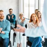 Large group of happy entrepreneurs applauding on a business seminar in the office.