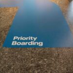 Blue priority boarding lane painted on airport terminal floor leading to a plane boarding