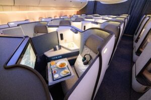 A table with food and headphones on it in an airplane.