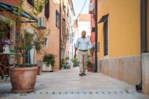Mature Hispanic Man Strolling Through Quaint Coastal Town Alley on a Sunny Day