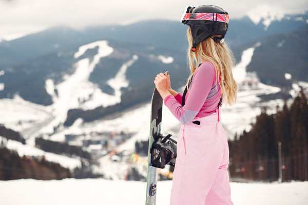 Girl snowboarding in the mountains with the snowboard